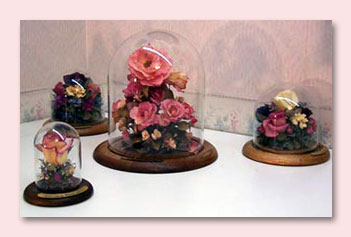 Four table domes of various sizes with the same preserved pink roses