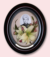 preserved lilies under photo of lady encased in dark brown oval frame with custom engraving
