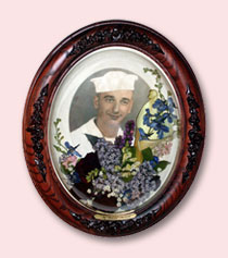 photo of deceased sailor with preserved funeral flowers in brown frame encasement with decorations and engraving