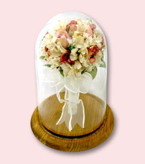 preserved bridal bouquet standing upright in glass dome with oak base