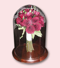 wedding bouquet of red roses preserved under glass dome with wood base