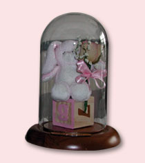 pink baby memorabilia keepsake in table dome with brown wood base