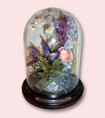 table dome with brown wood base contains preserved funeral florals and a photo of a lady
