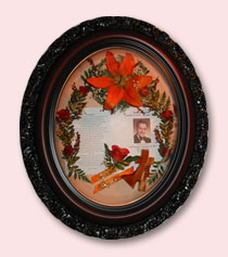 orange lily preserved with photo of man and funeral announcement in brown ornate frame
