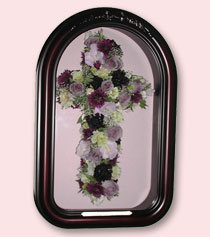 a brown cathedral shaped shadow box with a cross created out of preserved funeral flowers
