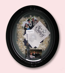 graduation lei flowers preserved with photos, announcement, and tassle in brown oval frame
