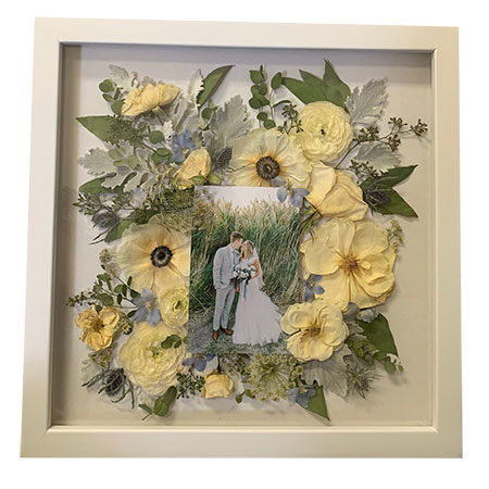 Pressed yellow roses with green foliage and photo of wedding couple